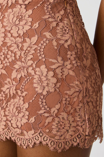 Close-up of a lace garment with intricate floral patterns on a plain background