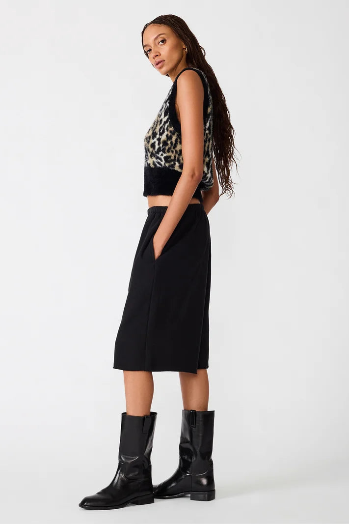 side view of woman in leopard print vest and black pants
