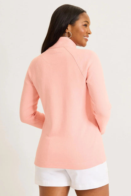 Woman wearing a pink blazer and white shorts on a light background