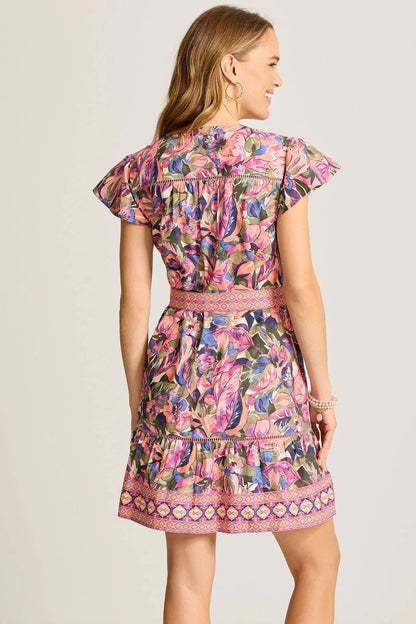 Woman wearing a colorful floral dress on a plain background