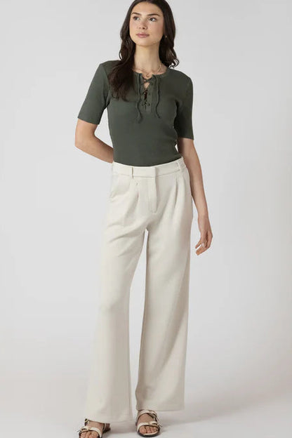 Woman wearing a green top and beige pants on a white background