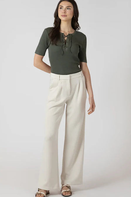 Woman wearing a green top and beige pants on a white background