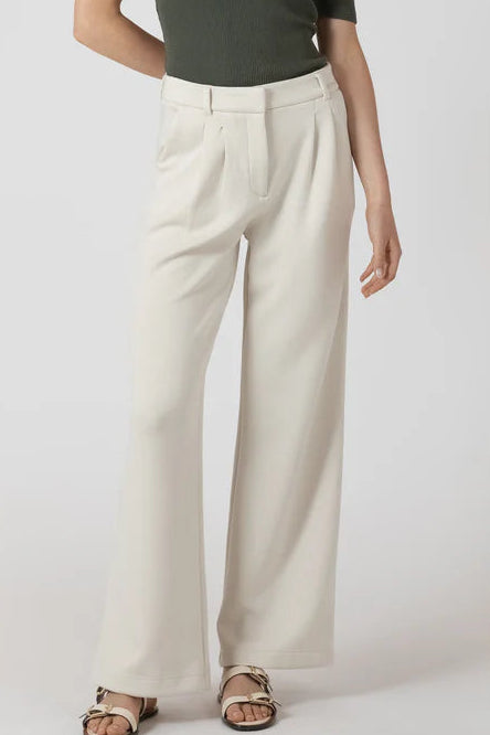 Person wearing beige wide-leg pants on a white background