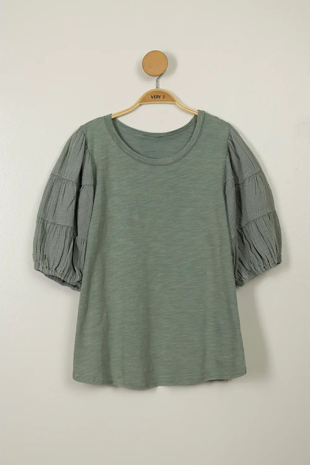 Green dress with puff sleeves on a hanger against a white background