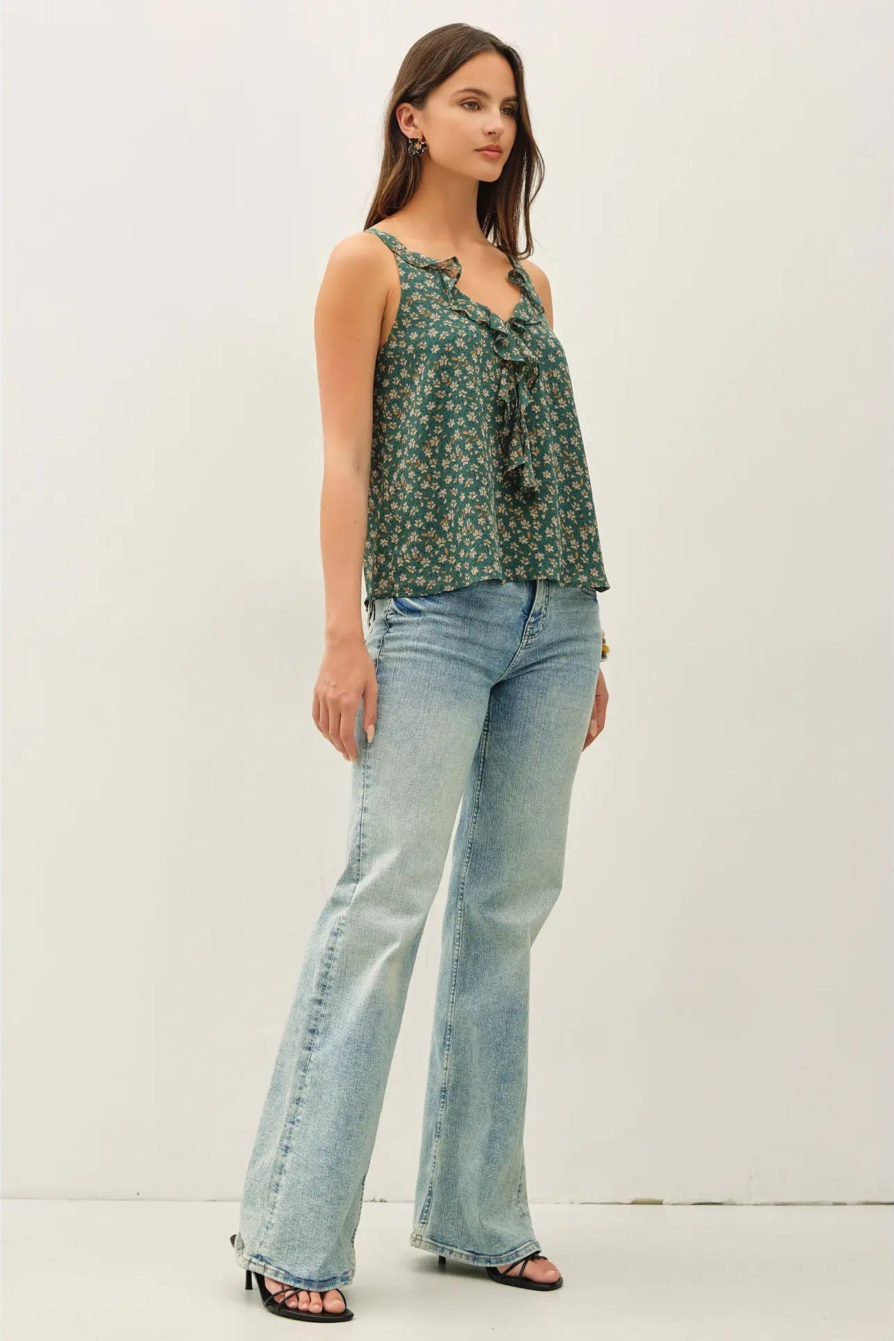 Woman wearing a green floral top and blue jeans on a white background