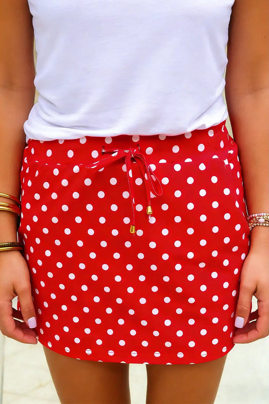 Red polka dot skirt with white top on a neutral background
