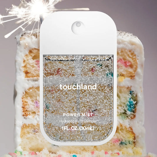 Touchland power mist in front of a colorful cake with sparklers