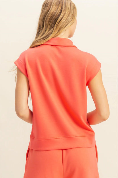 Person wearing a coral sleeveless top and pants on a beige background