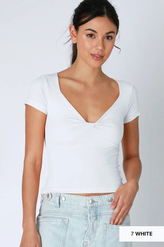 Woman wearing a white crop top and light blue jeans on a plain background