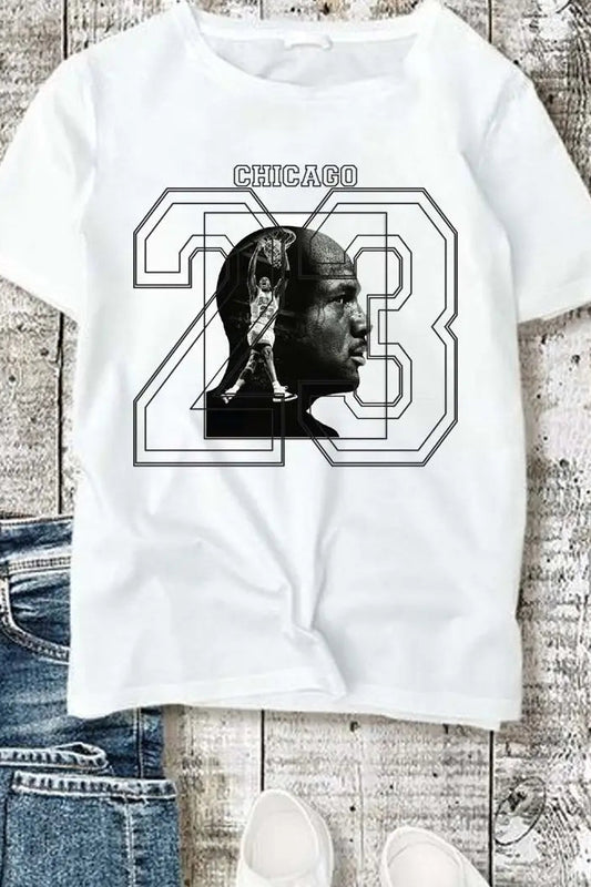 White t-shirt with graphic design featuring a silhouette and 'Chicago 23' text on a wooden surface.