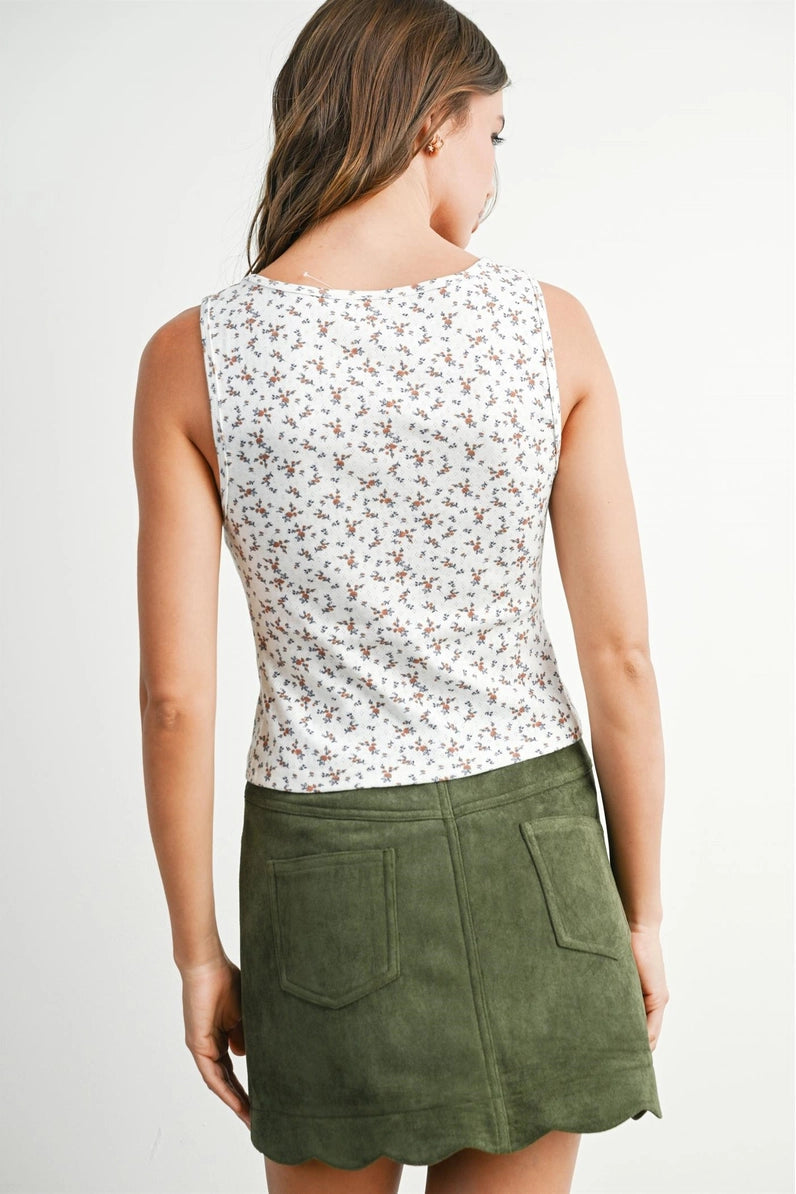 Woman wearing a floral sleeveless top and green skirt on a white background