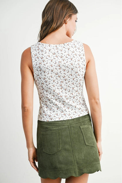 Woman wearing a floral sleeveless top and green skirt on a white background