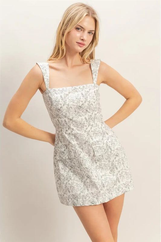 Woman wearing a white floral dress against a plain background