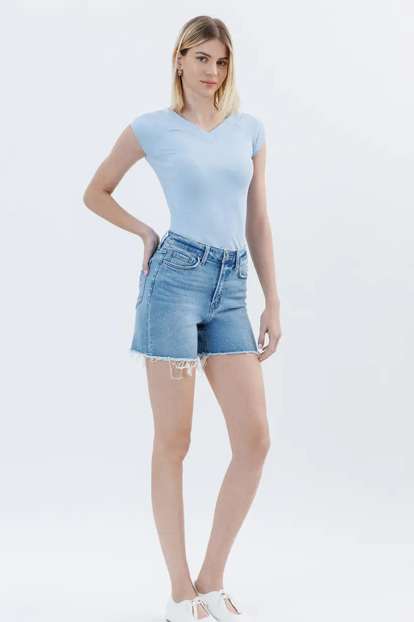 Woman wearing a light blue t-shirt and denim shorts on a white background