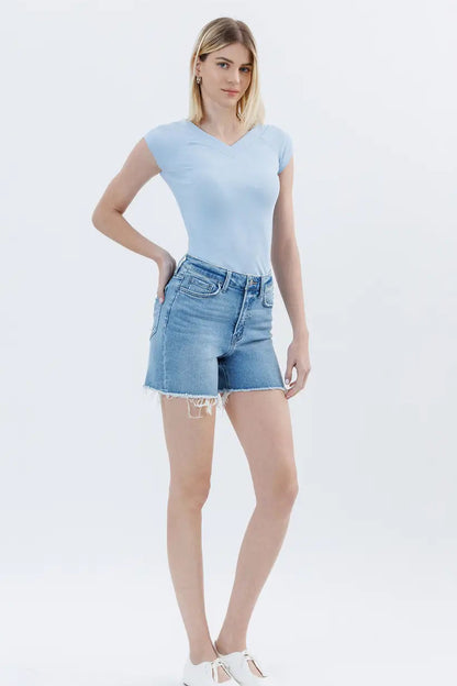 Woman wearing a light blue t-shirt and denim shorts on a white background