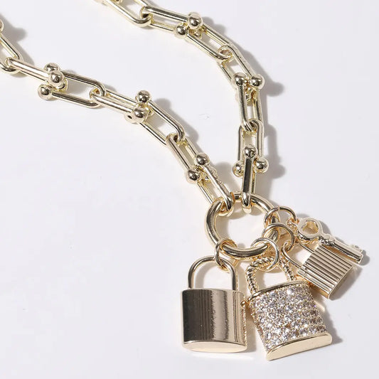 Gold chain bracelet with padlock charms on a white background