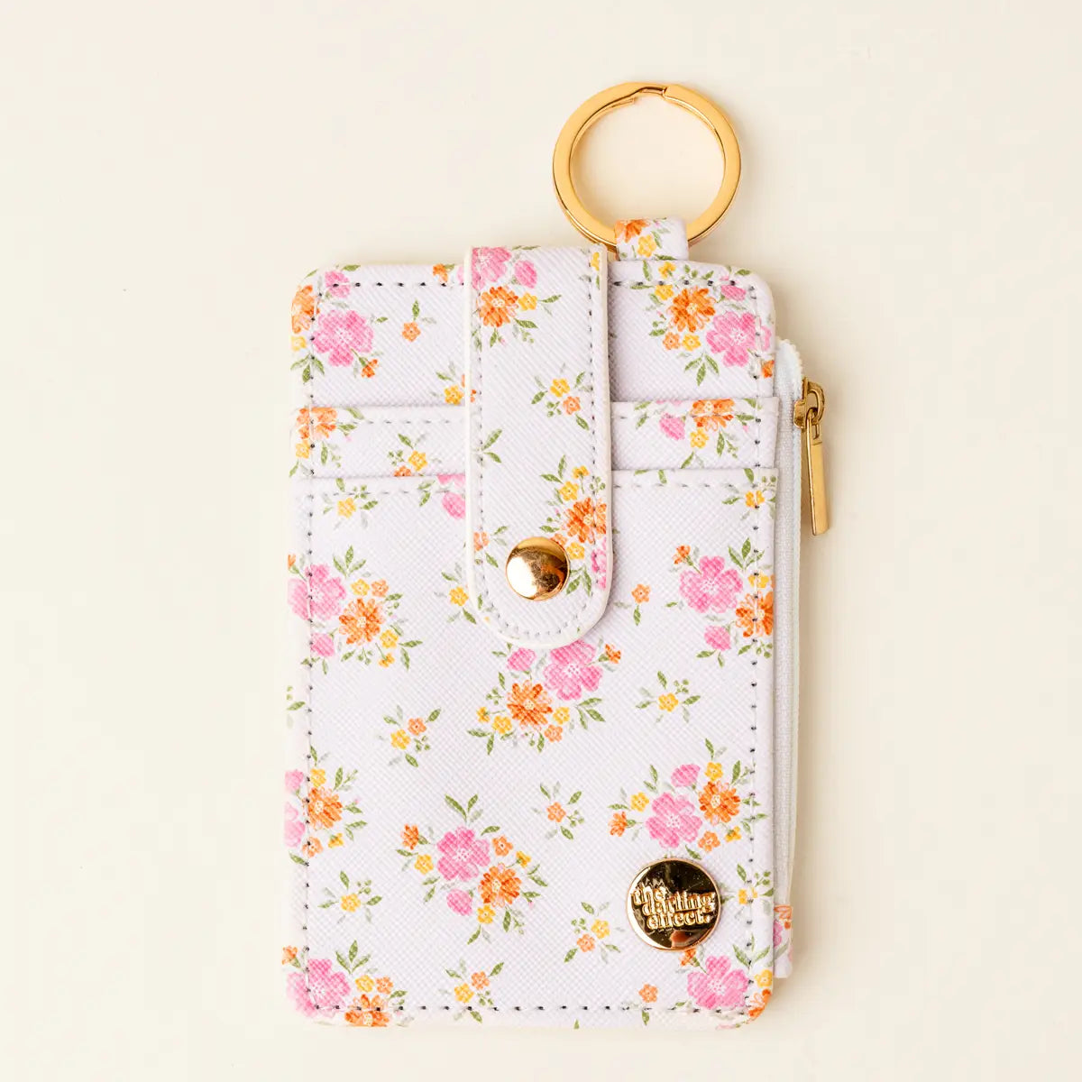 Floral-patterned keychain pouch with a gold ring on a beige background