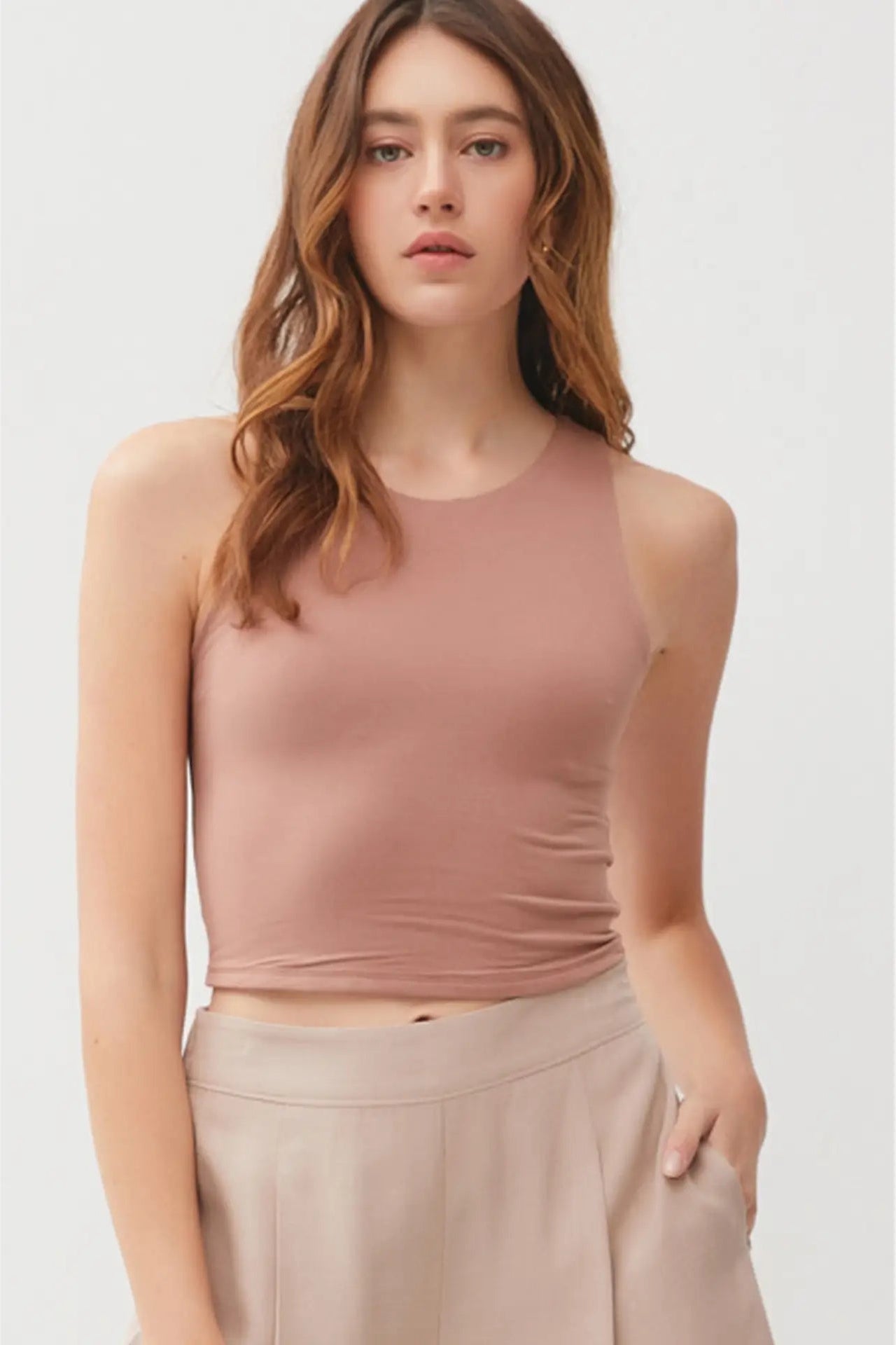Woman wearing a mauve sleeveless top and pants on a white background