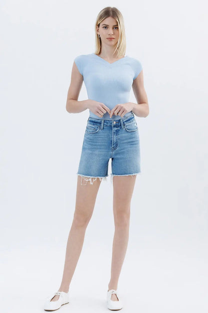 Woman wearing a light blue top and denim shorts on a white background