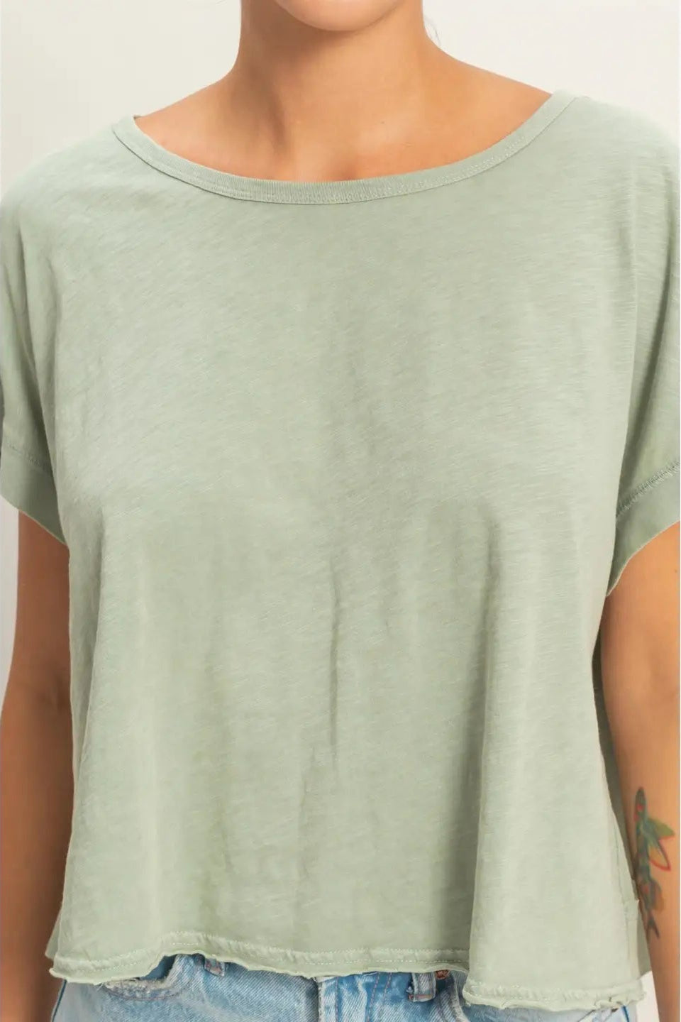 Person wearing a light green t-shirt with a plain background