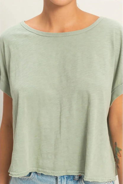 Person wearing a light green t-shirt with a plain background