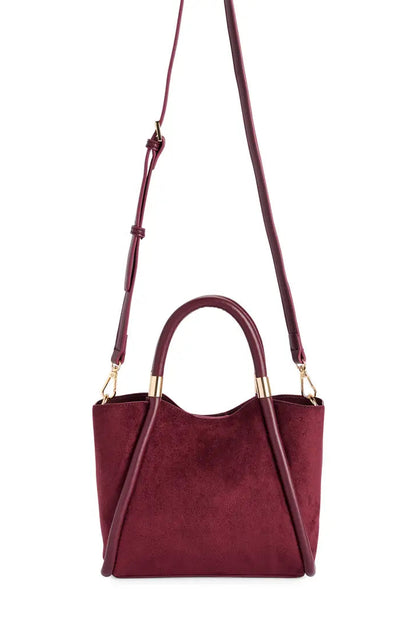 A burgundy suede crossbody handbag with a top handle, gold-tone hardware, and a matching adjustable shoulder strap, shown against a plain white background.