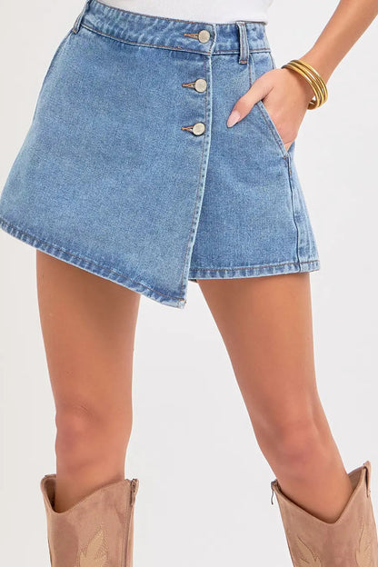 Denim skirt worn by a person on a plain background
