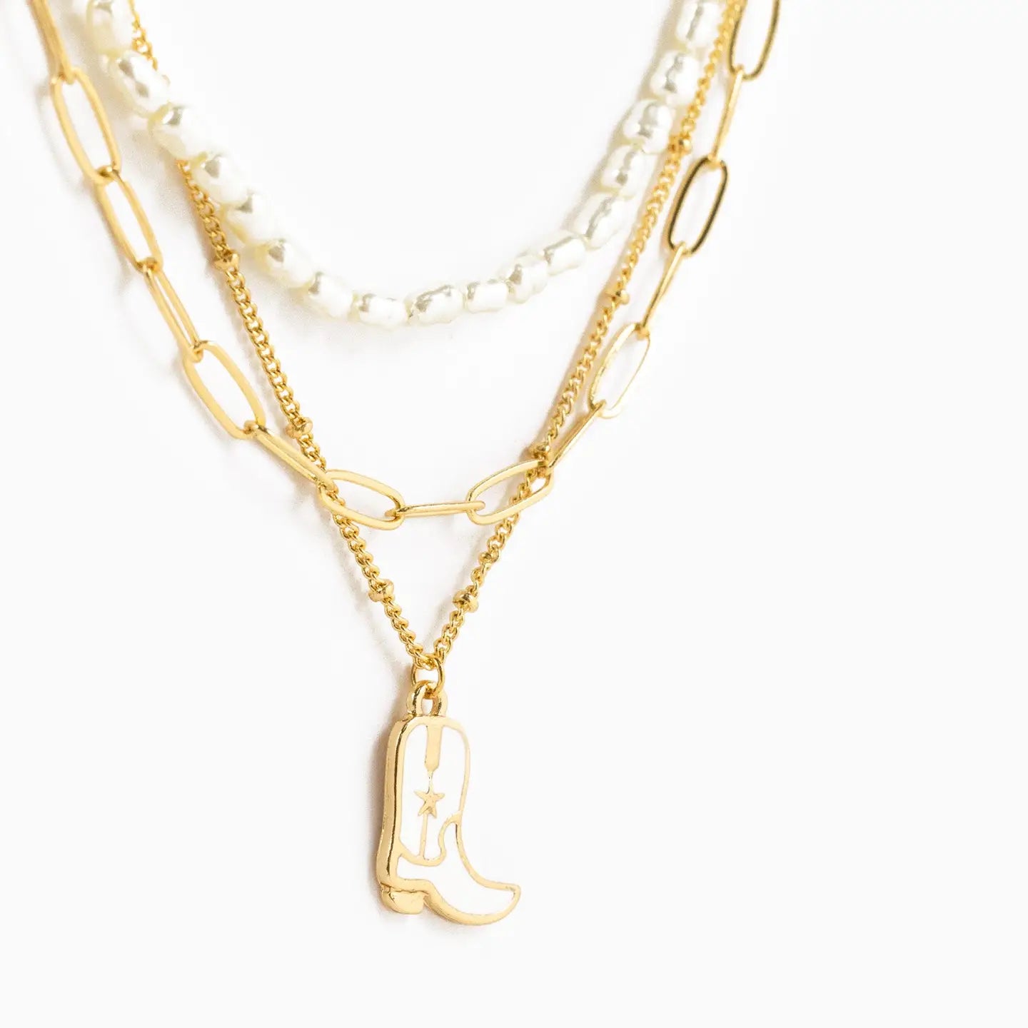 Gold necklace with a cowboy boot charm on a white background
