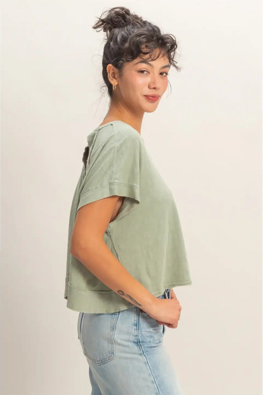 Woman wearing a green t-shirt and blue jeans against a plain background