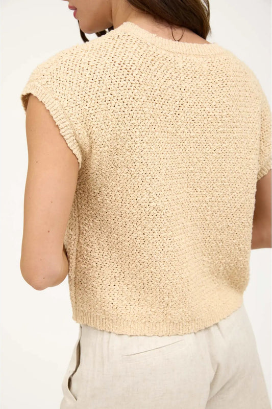 Beige knitted sleeveless top worn by a person on a white background