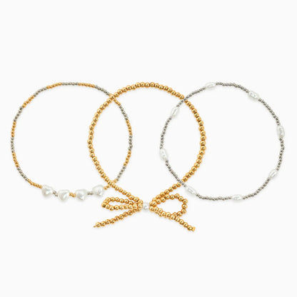 Three beaded hair ties in gold, silver, and a mix of both on a white background.