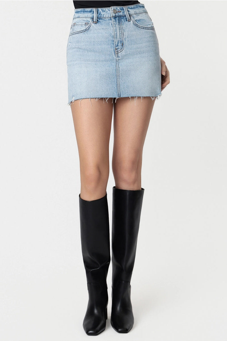 Person wearing a light blue denim skirt and black knee-high boots on a white background