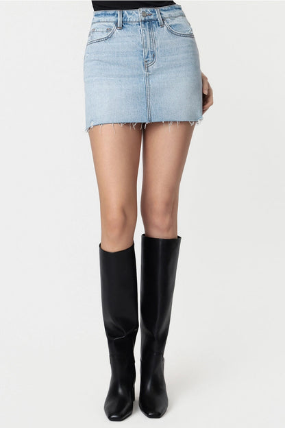 Person wearing a light blue denim skirt and black knee-high boots on a white background