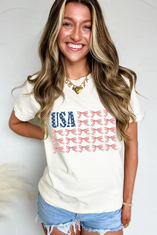 Woman wearing a white t-shirt with 'USA' and bow designs, standing against a plain background.