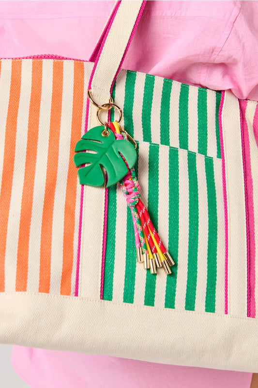 Striped bag with a green leaf keychain on a pink background