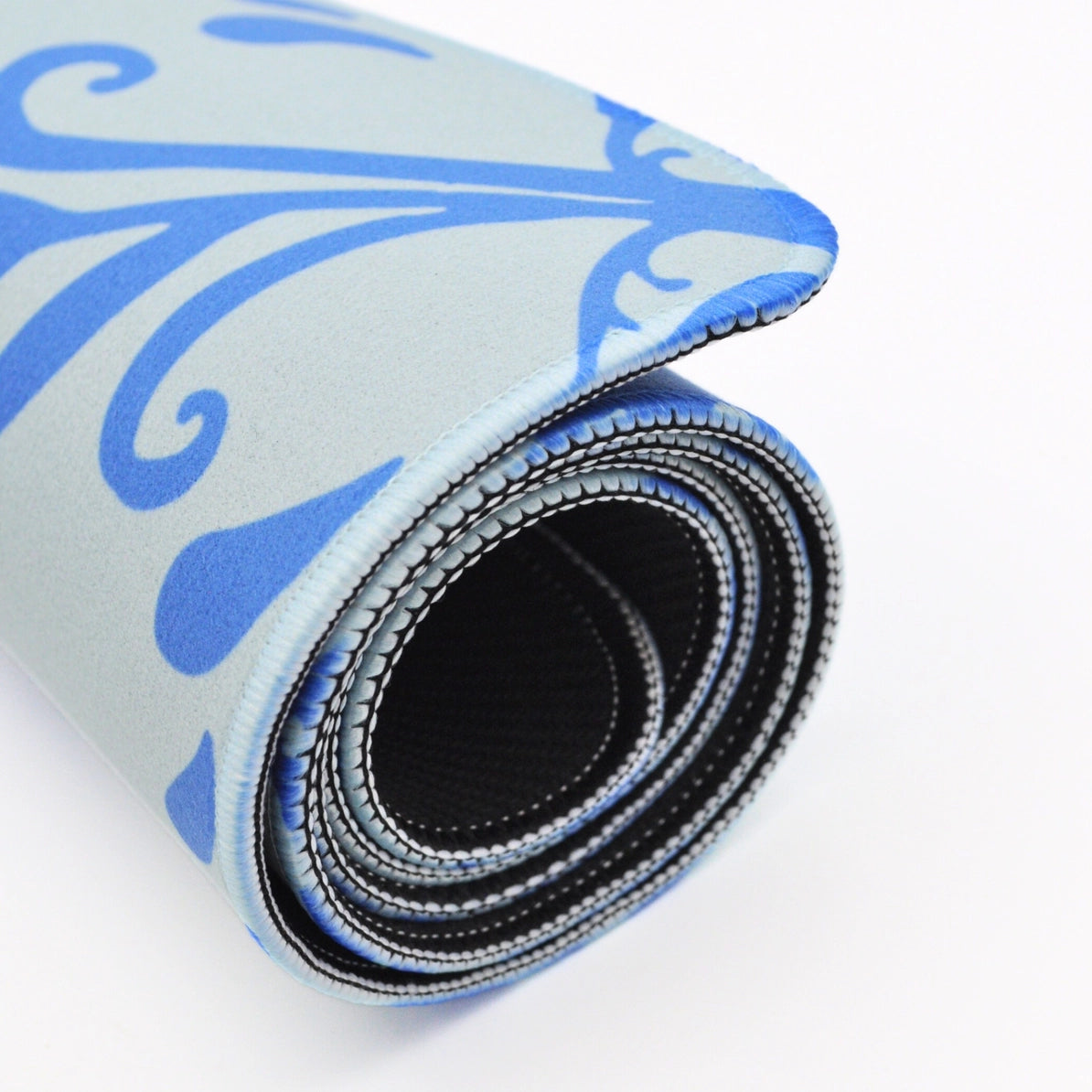 A rolled-up exercise or yoga mat with a light blue and blue patterned top surface and a black textured underside, shown on a white background.