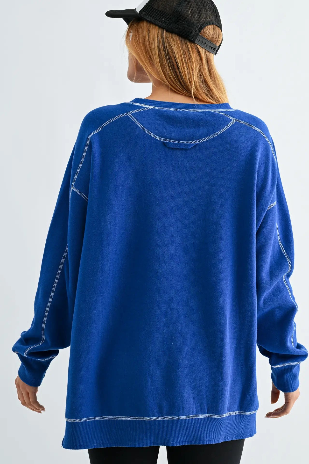 Person wearing a blue sweatshirt with white accents on a plain background