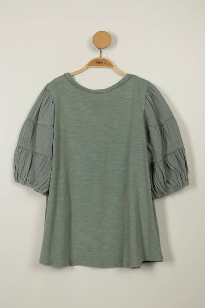 Green dress with puff sleeves on a hanger against a beige background