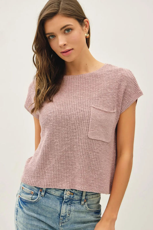 Woman wearing a pink textured top with a pocket on a white background