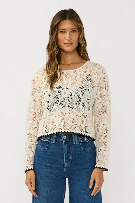 Woman wearing a lace top and blue jeans on a white background