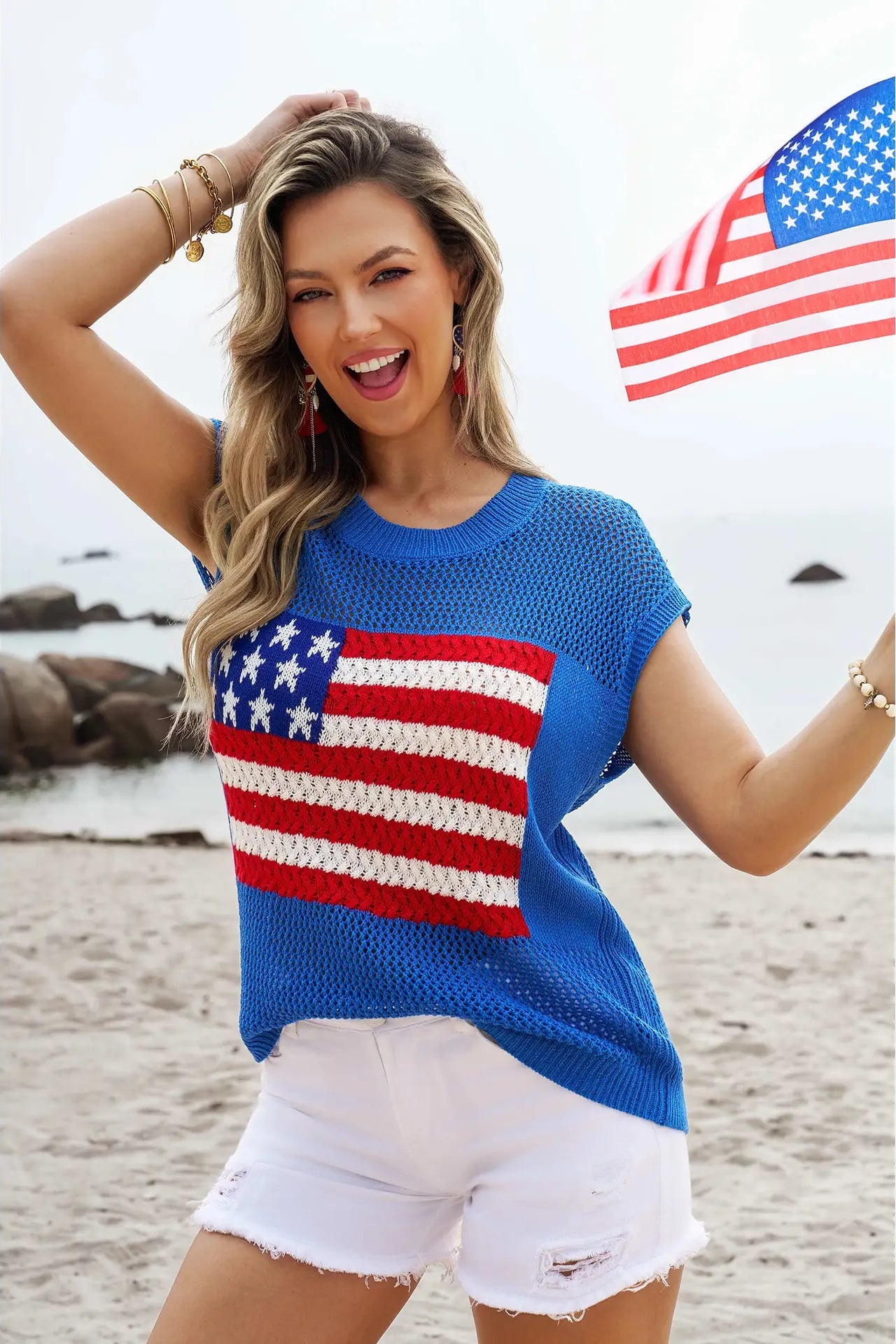 Woman wearing a blue sweater with an American flag design on a beach.