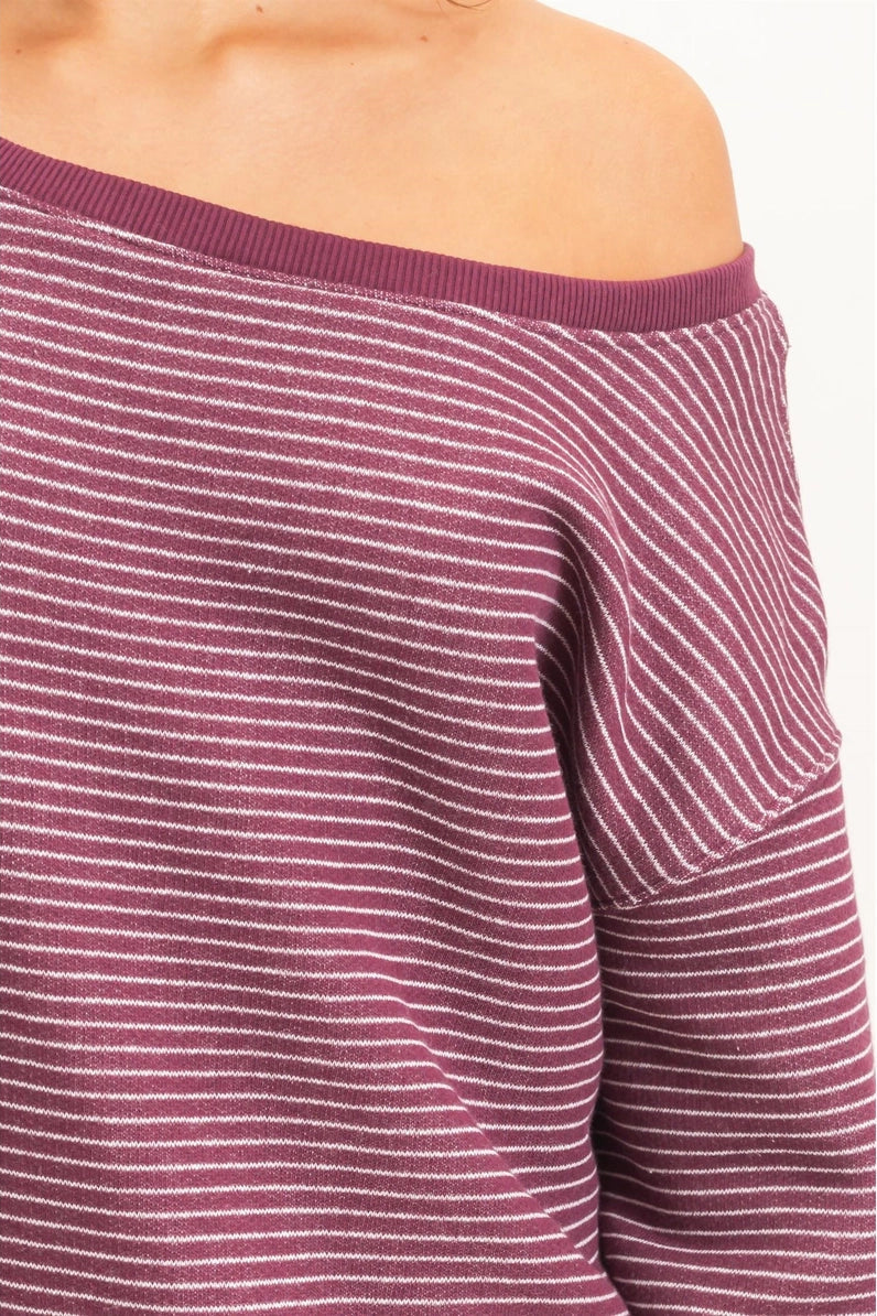 Close-up of an off-the-shoulder long-sleeve knit top with thin white horizontal stripes on a dusty rose/mauve base, shown on a model against a plain light background.