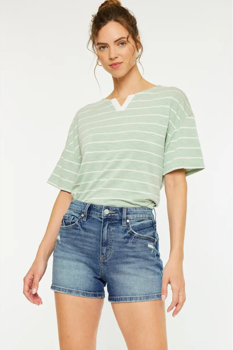 Woman wearing a striped shirt and denim shorts on a white background