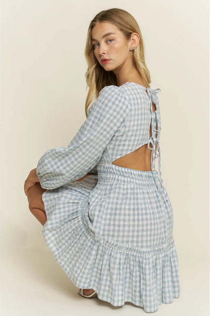 Woman wearing a blue and white checkered dress with cut-out design on a beige background