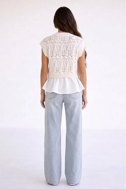 A woman viewed from the back wearing a white sleeveless knit top with a textured pattern and ruffled hem, paired with light-wash wide-leg jeans, against a plain white studio background.