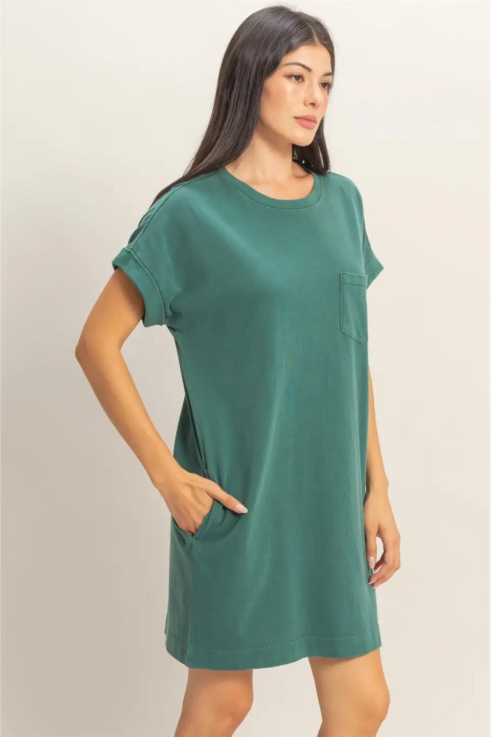Woman wearing a green t-shirt dress against a plain background