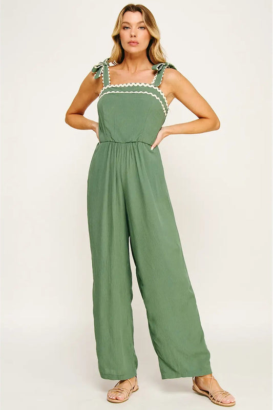 Woman wearing a green jumpsuit with lace details on a white background