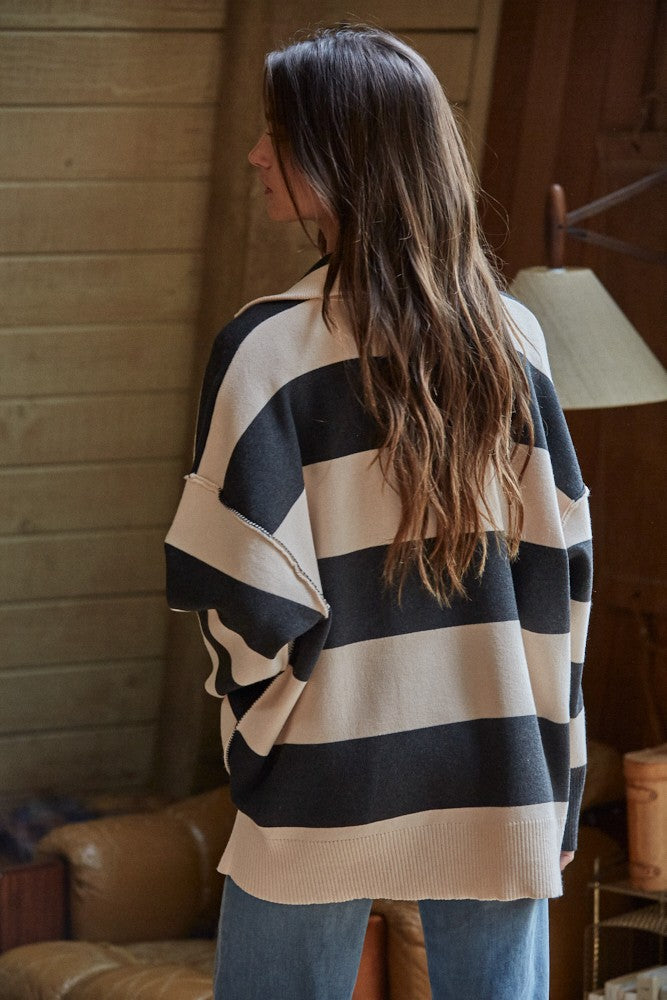 Person wearing a black and beige striped sweater in an indoor setting