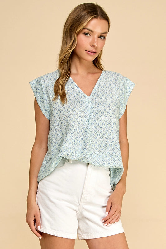 Woman wearing a light blue floral top and white shorts on a beige background