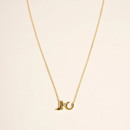 Gold necklace with a unique pendant on a beige background